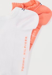 Βαμβακερές κάλτσες αστραγάλου σε λευκό και κοραλί, με ριμπ υφή, ελαστικές μανσέτες και εκτυπωμένο λογότυπο "TOMMY HILFIGER" σε αντιθετικά χρώματα.