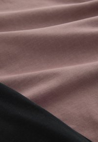 Tissu en coton mauve et noir, présentant des surfaces lisses légèrement texturées avec des plis subtils et des nuances variées dans une disposition en couches.