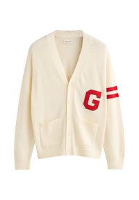 Cardigan crema con scollo a V, caratterizzato da una grande patch rossa con la lettera "G" e due strisce rosse sulla manica sinistra. Include due tasche frontali.