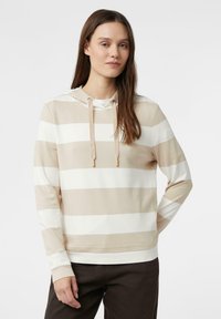 Beżowo-biała bluza z kapturem w paski, z troczkiem, wykonana z miękkiej tkaniny, z długimi rękawami i luźnym krojem. Nosi się ją na ciemnobrązowych spodniach.