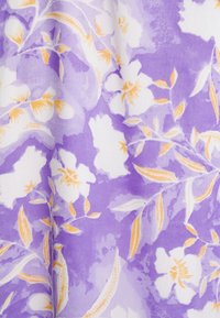 Tecido estampado com um fundo lavanda, flores brancas e detalhes laranja. Textura suave com desenhos florais e de folhas.