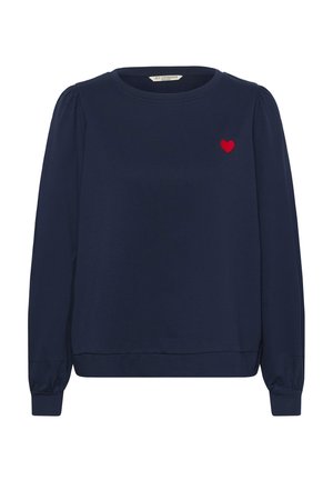 Mornarsko modra jopa z dolgimi napihnjenimi rokavi, okroglim izrezom in rdečim vezenjem srca na levi strani prsnega koša. Mehka tekstura in elastični manšeti.