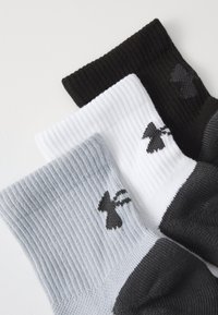Tres pares de calcetines de canalé en gris, blanco y negro, cada uno con un logo en negro contrastante en el lateral de los puños.