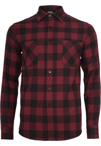 Camicia di flanella a quadri rossi e neri con maniche lunghe, chiusura a bottoni frontale, due tasche sul petto e colletto classico. Tessuto morbido.