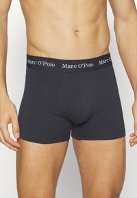 Tummanharmaat bokserit, jotka on valmistettu puuvillasta ja joissa on brändätty joustava vyötärönauha, jossa lukee "Marc O'Polo" valkoisella tekstillä. Sujuva pinta, istuva malli.