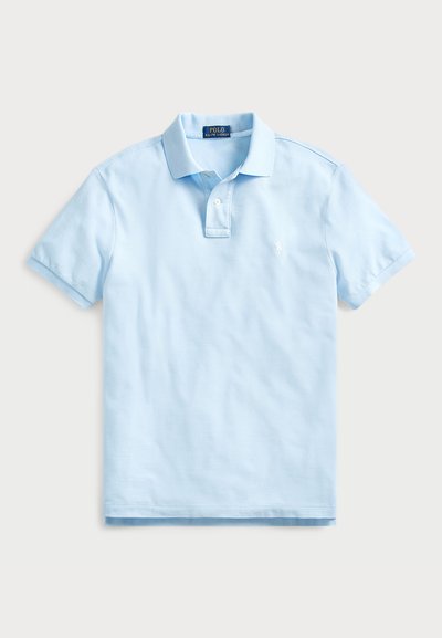 Vaaleansininen puuvillapolo, jossa on käännettävä kaulus, kolmonen napilla ja pieni brodeerattu logo vasemmassa rinnassa. Lyhyet hihat.