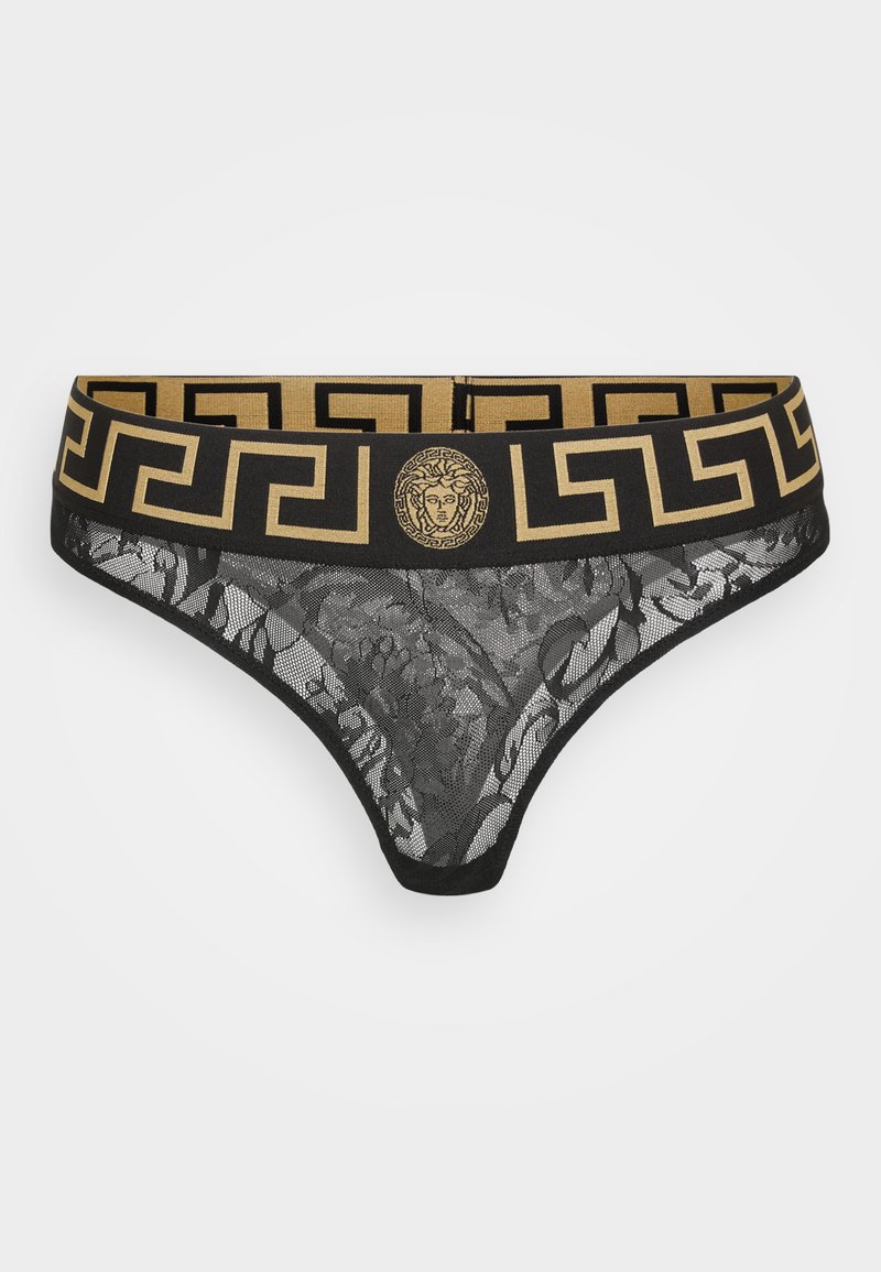 Black lace thong with a gold elastic waistband featuring a geometric pattern and a central Versace emblem. Intricate floral details in the lace.