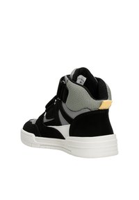 Baskets mi-hautes noires et grises en matières suédées et en mesh, semelle blanche, sangle ajustable et accent jaune au niveau du talon.