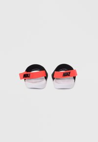 Σανδάλια Nike με μαύρο αφρώδες πάνω μέρος, ρυθμιζόμενο πορτοκαλί λουράκι με λογότυπο και λευκή λαστιχένια σόλα. Υφασμένο πέλμα για καλύτερη πρόσφυση.