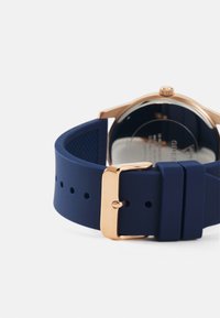 Brățară pentru ceas din silicon de culoare navy cu cataramă aurie, evidențiind o textură netedă și un design minimalist, asortată cu un cadran de ceas din aur roz.