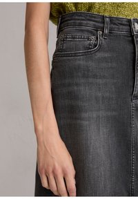 Hoge taille denim rok in donkergrijs met een gladde textuur. Voorzien van zijzakken en metallic knoopaccenten, gezien vanaf de zijkant.