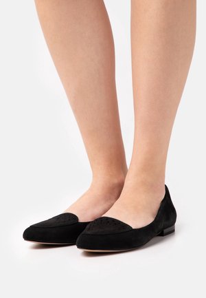 Schwarze Wildleder-Ballerinas mit runder Zehenpartie und dekorativem durchbrochenem Akzent. Niedriger Absatz, elegantes Design und weiche Textur. Minimalistischer Stil.