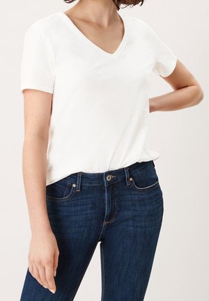 Hvid kortærmet V-hals T-shirt lavet af blødt stof, kombineret med mørkeblå slim-fit jeans med klassiske syninger og forlommer.