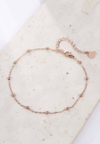 Pulsera de oro rosa que presenta una delicada cadena con cuentas redondas espaciadas uniformemente. Cierre ajustable con un detalle de charm en forma de corazón.