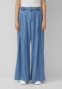 Heledad sinine, laiad säärised denim-püksid vertikaalsete triipudega, volditud eesmine osa ja tekstuuriga vöökoht. Valmis tavaliseks ääreks ja kergeks lõdvenduseks.
