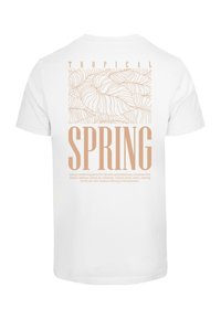 Hvid bomulds t-shirt med et "Tropical Spring" grafik med lysebrune bogstaver og et bladmønster på ryggen.