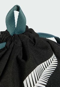 Bolsa de tela negra con cordón y asas en color teal, que presenta un diseño gráfico de helecho blanco en un lado. Textura suave, cierre en la parte superior con fruncido.