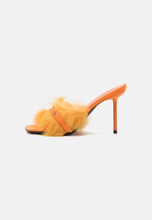 Oranžinės aukštakulnės mules, turinčios pūkuotą geltoną kailio juostą viršuje ir lygų oranžinį dirželį. Juodas padas su smailiu pirštu.