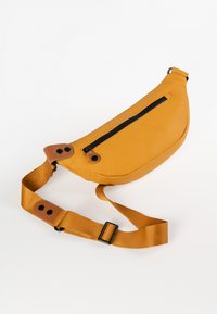 Borsa a tracolla gialla realizzata in materiale morbido, con una cerniera nera frontale, dettagli marroni e una tracolla regolabile. Design a forma curvata.