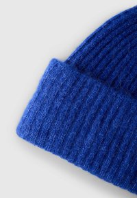 Beanie a costine blu con una trama morbida, caratterizzato da un risvolto. Il materiale appare soffice e caldo, adatto per il freddo.