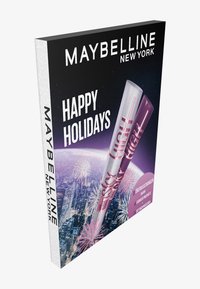 L'emballage des fêtes de Maybelline New York présente un fond noir, des tubes de mascara argentés et violets, et un texte blanc audacieux indiquant "Joyeuses Fêtes".