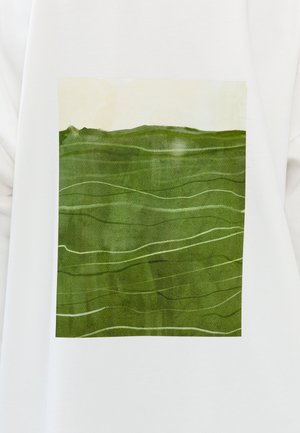 Maglietta bianca con una grafica rettangolare di un paesaggio verde caratterizzata da onde testurizzate e dettagli verde chiaro su uno sfondo pallido.