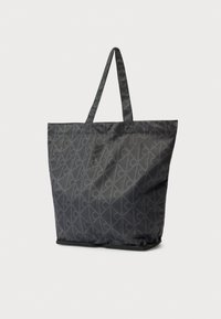 Čierna taška na rameno s geometrickým vzorom, vyrobená z odolnej látky. Má dve rúčky a spodnú časť so zipsom pre bezpečné zatvorenie.