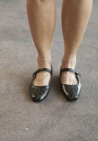 Zwarte ballerina's van slangenleer met een vierkante neus en een enkele band over de wreef, met een gladde textuur en een elegante uitstraling.