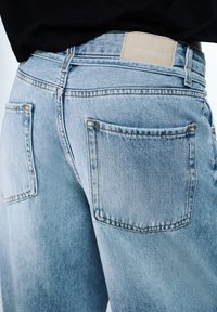 Světle modré džíny z denimu s vysokým pasem, dvěma zadními kapsami a koženou nášivkou s nápisem "PULL&BEAR" na pásku.