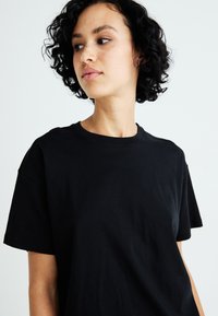 Zwarte katoenen t-shirt met een ronde hals en korte mouwen, voorzien van een zachte textuur en een relaxte pasvorm.