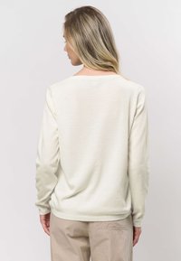 Licht beige lange mouw sweatshirt met een ronde hals, zachte textuur en geribbelde manchetten. Ontworpen voor een relaxte pasvorm met een eenvoudige stijl.