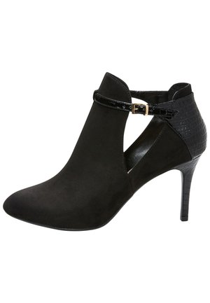 Bota de ante negro de tacón alto hasta el tobillo con laterales recortados, tacón y parte trasera con textura de cocodrilo brillante y una fina correa en el tobillo con hebilla dorada.