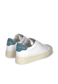 Baskets blanches avec une tige en cuir lisse, des accents en daim bleu au niveau du talon et une semelle en caoutchouc beige. Quincaillerie décorative sur la languette.