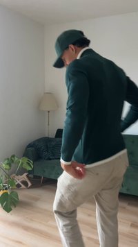 Groen gebreide trui met een slanke pasvorm, kaki broek en een bijpassende groene pet. De trui heeft geribde manchetten en eronder een wit overhemd.