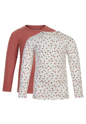 Twee langmouw tops: de ene in een effen stofroze, de andere in het wit met een rode bloemenpatroon. Beide hebben een ronde halslijn en een zachte stof.