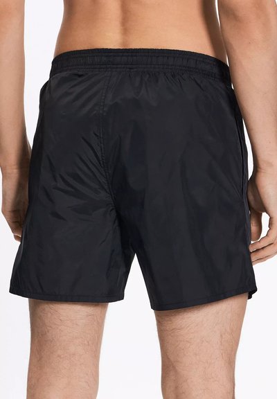 Pantaloni da bagno neri realizzati in materiale leggero e ad asciugatura rapida. Presentano una vita elasticizzata e un minimo dettaglio di cuciture per garantire comfort.