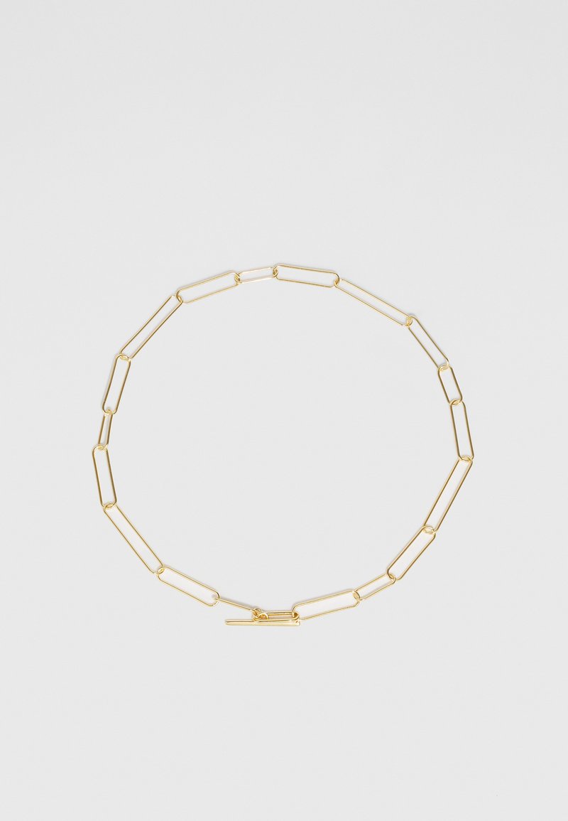 Guld kæde med forlængerede, papirklip-stil led og en enkel lås. Glat tekstur med en poleret finish.