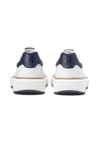 Bílé tenisky s tlustými texturovanými podrážkami, tmavě modré patní kapsy se zvýšeným logem, zobrazené zezadu na bílém pozadí.