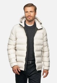 Vadderad jacka i ljusbeige med dragkedjestängning, fast huva och elastiska ärmslut. Har horisontell quiltning och två sidofickor.