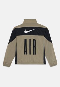 Nike αερόσακος μπουφάν σε ελαιόχρωμο και μαύρο, με ψηλό γιακά, ελαστικούς καρπούς και μεγάλο τύπωμα "AIR" στην πλάτη με το λογότυπο swoosh.