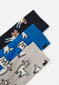 Three pairs of socks: dark blue with playful cows, bright blue with abstract designs, and light gray featuring llamas in a repeated pattern.