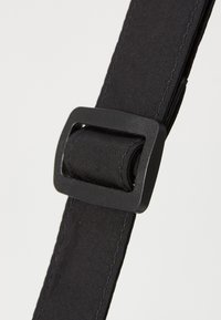 Correia de tecido preta com uma fivela retangular em metal preto, apresentando uma textura suave e bordas cosidas, projetada para comprimento ajustável.