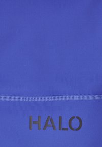 Blauwe stof met zichtbare horizontale naad boven het zwarte HALO-logo, gecentreerd op het materiaal.