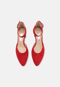 Röda mocka pumps med spetsig tå, tunn ankelrem och spänne. Slätt läderinlägg. Höjd: cirka 5 cm.
