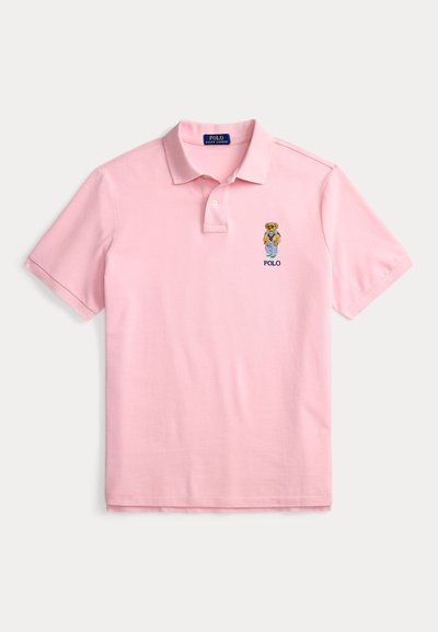 Light pink short-sleeve polo shirt with a small embroidered teddy bear wearing casual clothes and "POLO" text on the left chest.