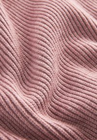 Texturiertes pinkes Gewebe mit schmalen, parallelen Rippungen. Das Material wirkt weich und gemütlich und zeigt subtile Farbnuancen.