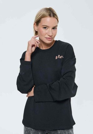 Sweatshirt noir avec un col rond, des manches longues et une coupe décontractée. Présente une broderie sur la poitrine. Texture de tissu douce.