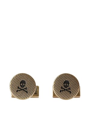 Gemelos de color bronce con textura estriada, que presentan un diseño central de calavera y tibias cruzadas en negro. Tienen forma circular y un cierre de metal.