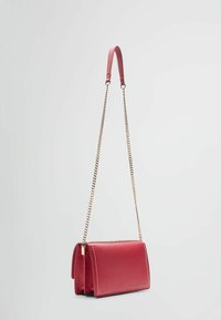 Bolso de cuero rojo tipo bandolera con correa de cadena, de forma rectangular, textura suave y costuras en blanco que contrastan en los bordes.