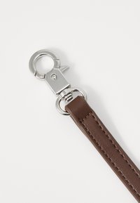 Cinturino in pelle marrone con una chiusura in metallo argentato, caratterizzato da una texture liscia e dettagli di cucitura lungo la lunghezza del cinturino.